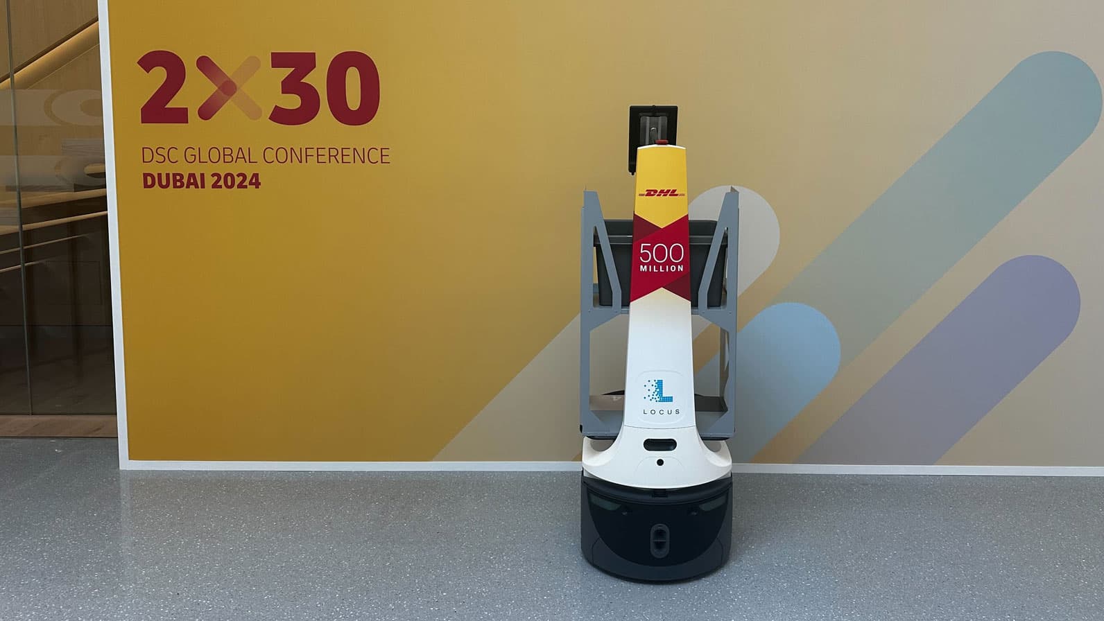 DHL warehouse workers operating alongside Locus Robotics autonomous mobile robots on a warehouse floor