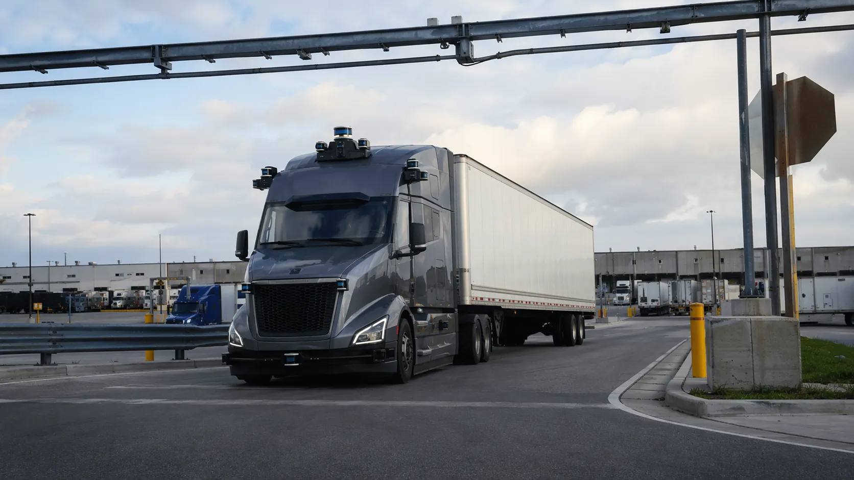 Autonomous truck with roof sensors making a slow right turn into a logistics distribution hub