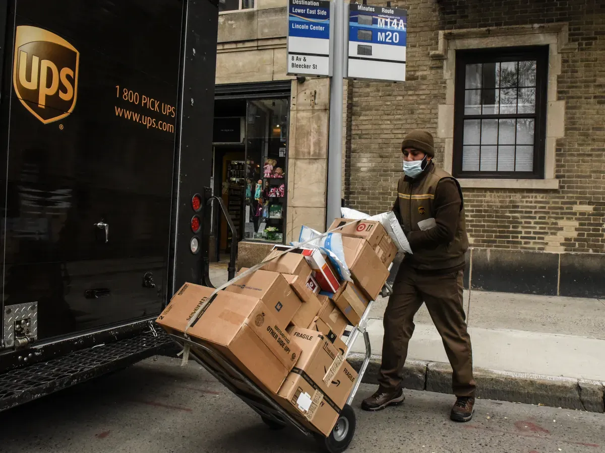 UPS delivery driver using a handheld routing device outside a delivery truck