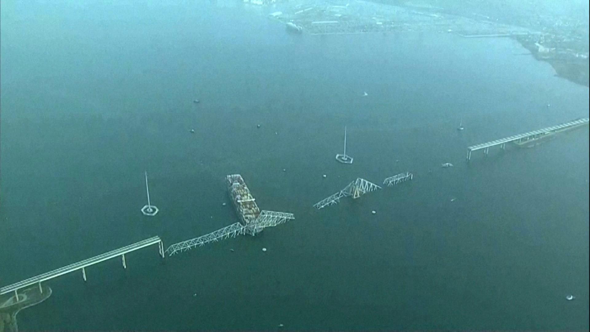 Aerial photograph of the collapsed Francis Scott Key Bridge in Baltimore with a cargo ship beneath the broken span