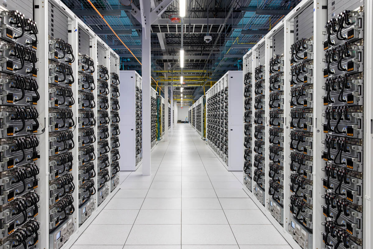 Rows of GPU servers and liquid cooling infrastructure inside the xAI Colossus data center compute hall