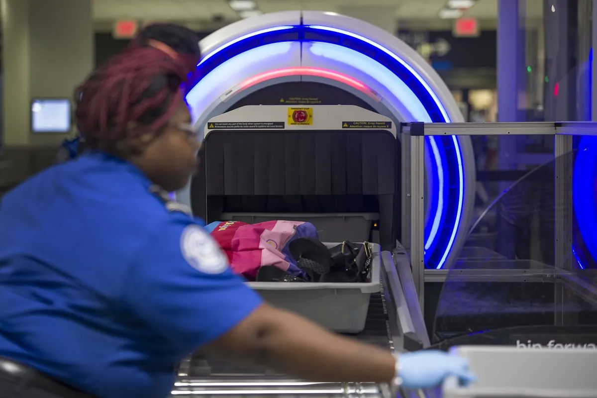 TSA computed tomography scanner at an airport checkpoint with conveyor belt and tunnel opening