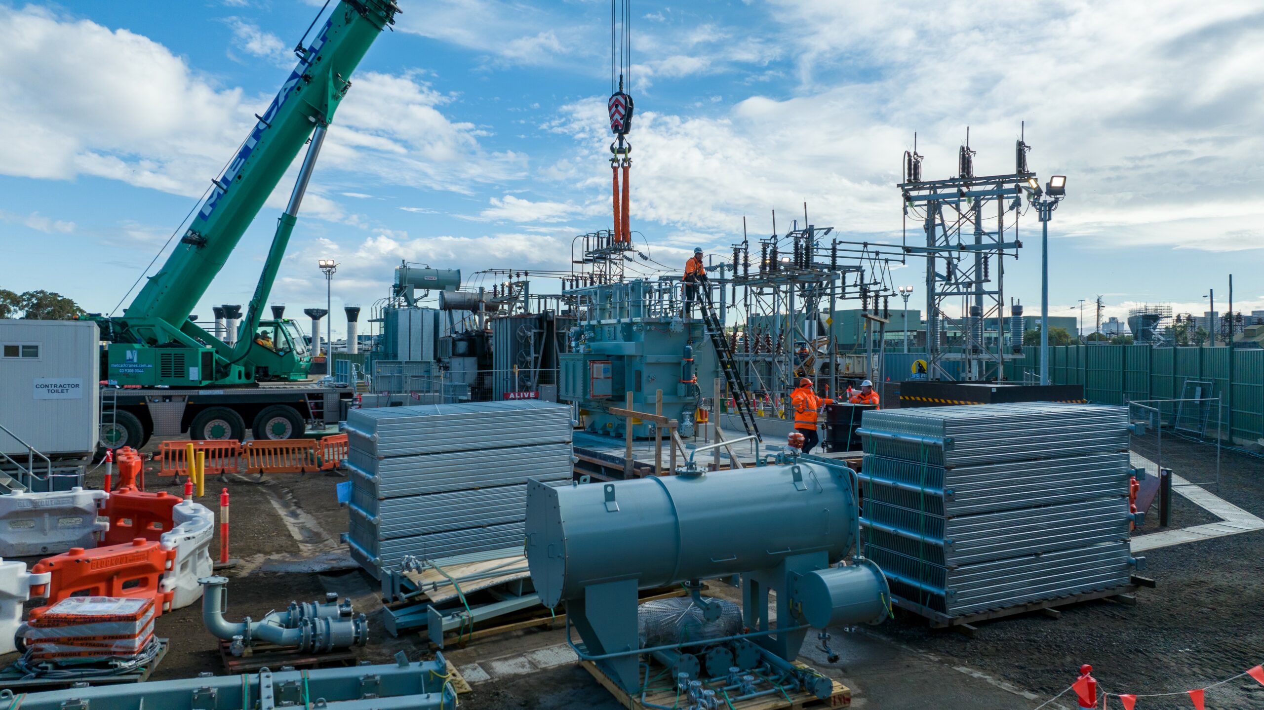 Large power transformer being lifted by crane during installation at an electrical substation