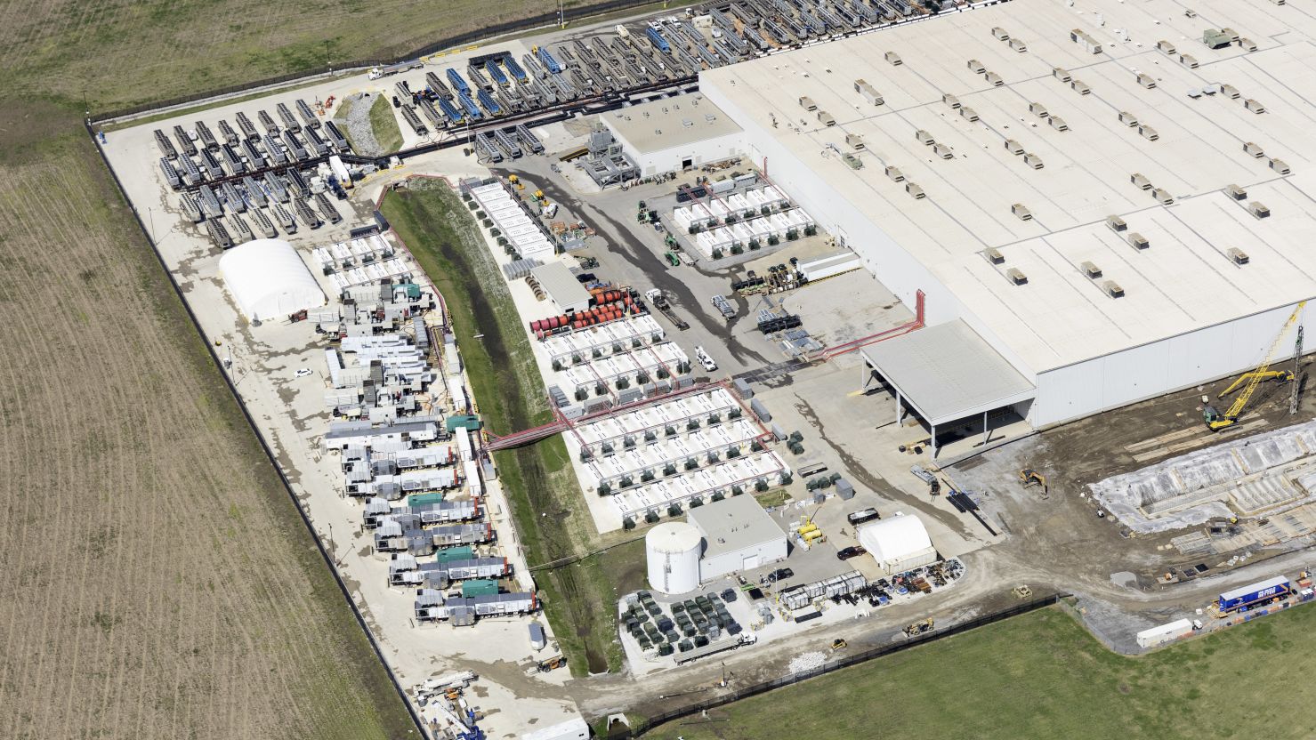 Aerial view of the Colossus data center complex with rows of mobile natural gas turbines beside the facility